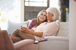 Grandmother With Adult Granddaughter Relaxing On Sofa